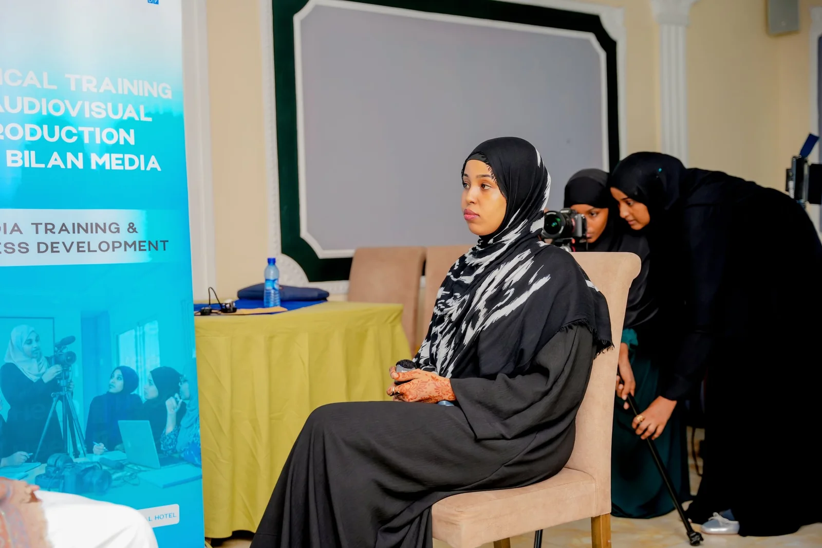 Participants setting up an interview recording beside the Technical Training on Audiovisual Production banner.