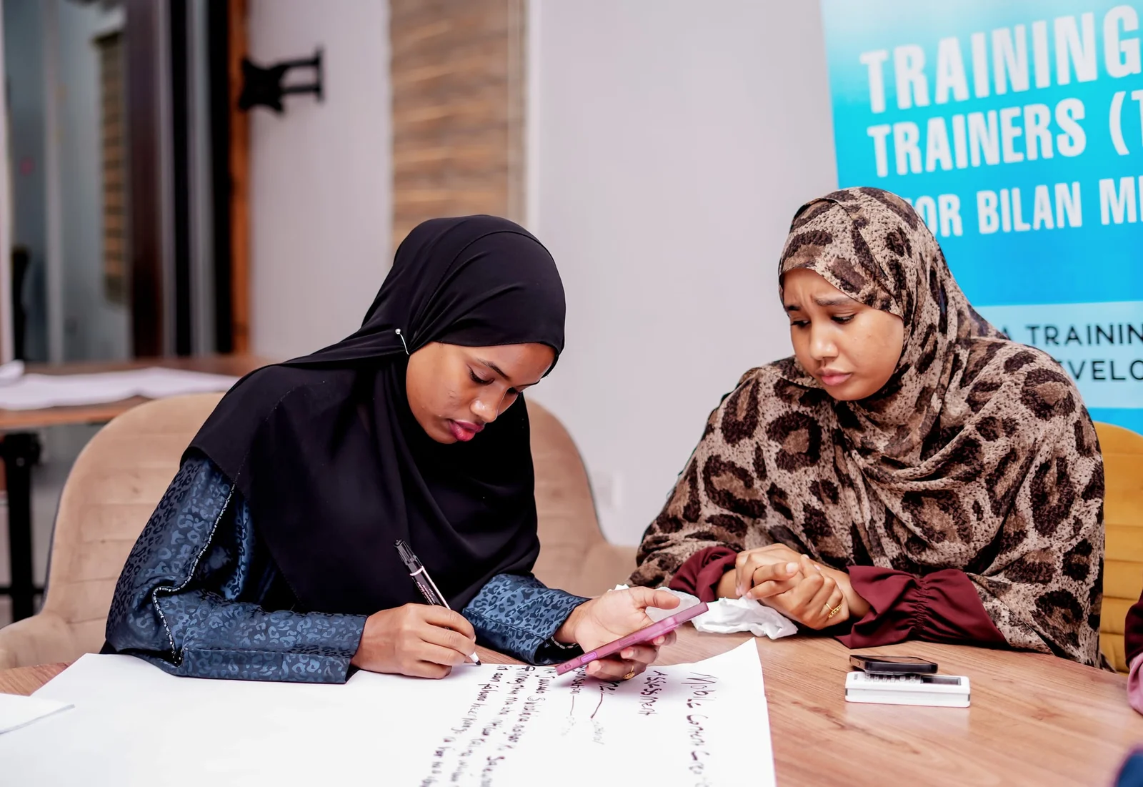 Participants drafting group work on flipchart paper during the Training of Trainers.