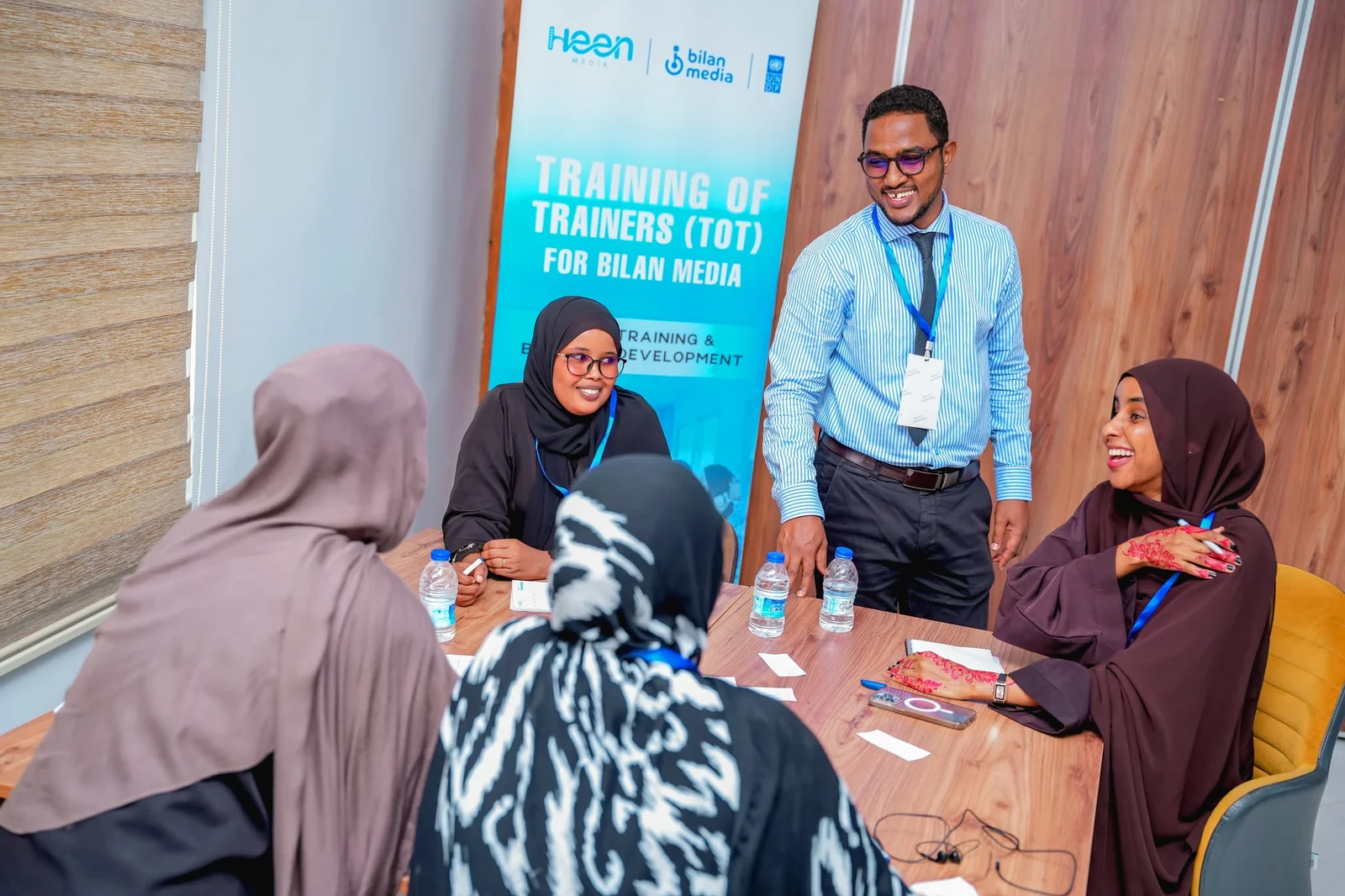 A facilitator working with a participant group beside the Training of Trainers banner in Mogadishu.