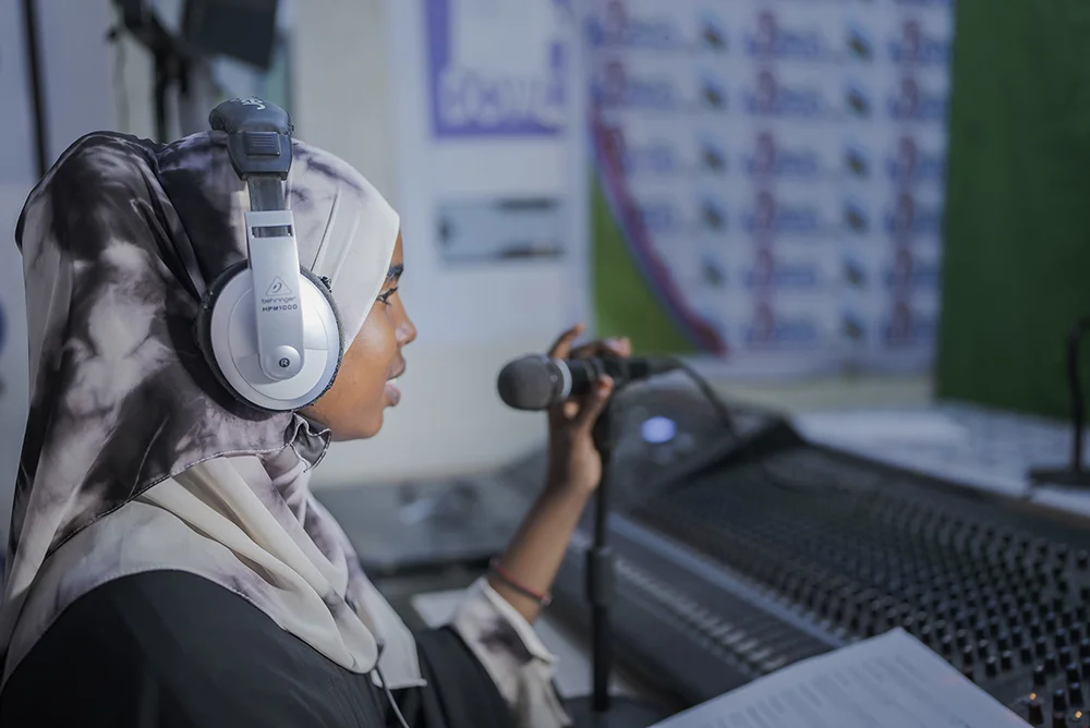 A journalist using headphones, a microphone and an audio mixer at Bilan and Dalsan in Mogadishu.
