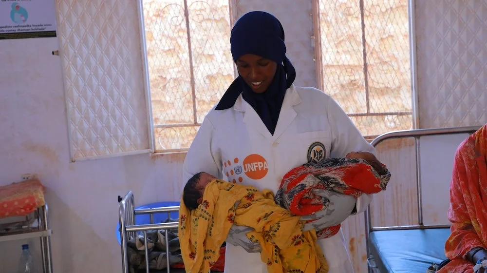 A midwife holding newborn twins at a healthcare facility in Baidoa.