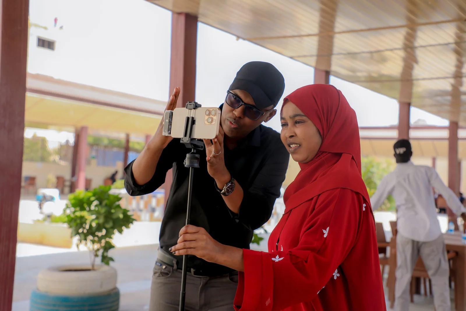 An instructor helping a participant record video using a smartphone and tripod at SNU in Mogadishu.