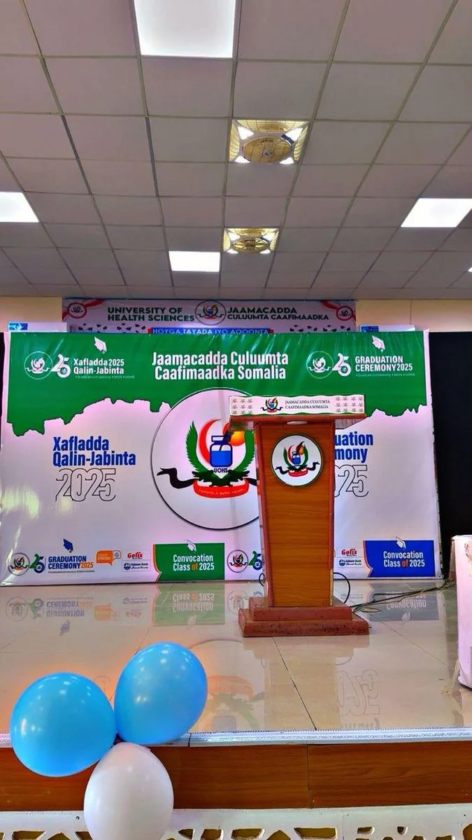 A printed graduation ceremony backdrop and podium at the University of Health Sciences Somalia.